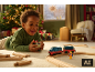 Glückliches Kind spielt am Weihnachtsmorgen mit einer Spielzeugeisenbahn.