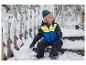 Ein lächelndes Kind im Schneeanzug und LUPILU® Schneestiefeln sitzt auf einer verschneiten Treppe.