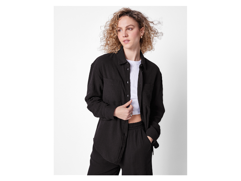 Model in einem schwarzen Baumwoll-Anzug, Hose und Hemd.