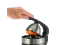 Eine Hand, die den Hebel einer Zitruspresse mit einer Orange darin nach unten drückt.