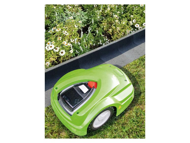 Grüner Mähroboter auf Rasen neben einem Blumenbeet mit weißen Blüten.