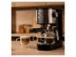 Kaffeemaschine mit zwei Espressotassen und einem Latte auf einer Holzarbeitsplatte.