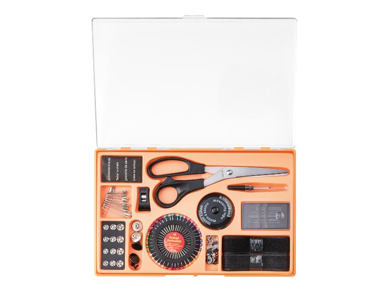 Nähset mit Schere, Stecknadeln, Maßband und Schneiderkreide in einer orangefarbenen Box.