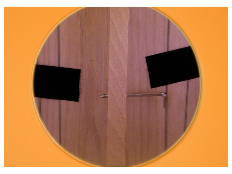 Eine Holzplatte mit zwei schwarzen Streifen, einer Schraube und einem Inbusschlüssel.