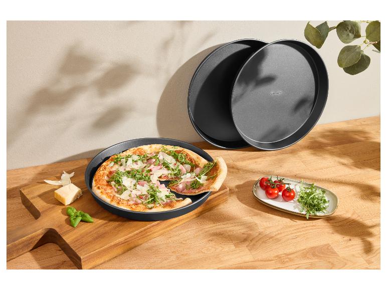 Frisch zubereitete Pizza in einer runden Backform, mit Tomaten und Rucola.