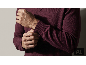 Mann passt das Bündchen eines weinroten Pullovers an.