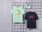 Zwei T-Shirts mit Aufdruck, ein grünes mit 'Pink Island Paradise' und ein schwarzes mit 'Sunset Moment'.