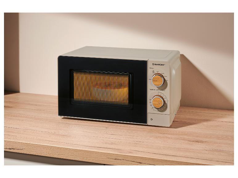 Beige Mikrowelle mit Holzbedienfeld, auf einem Holztisch.