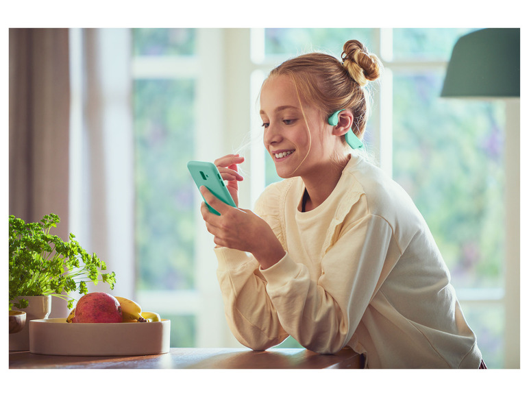 Ein Mädchen benutzt ihr Handy mit einem offenen Ohrhörer.