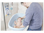 Ein Vater badet sein Baby in einer blauen Badewanne.