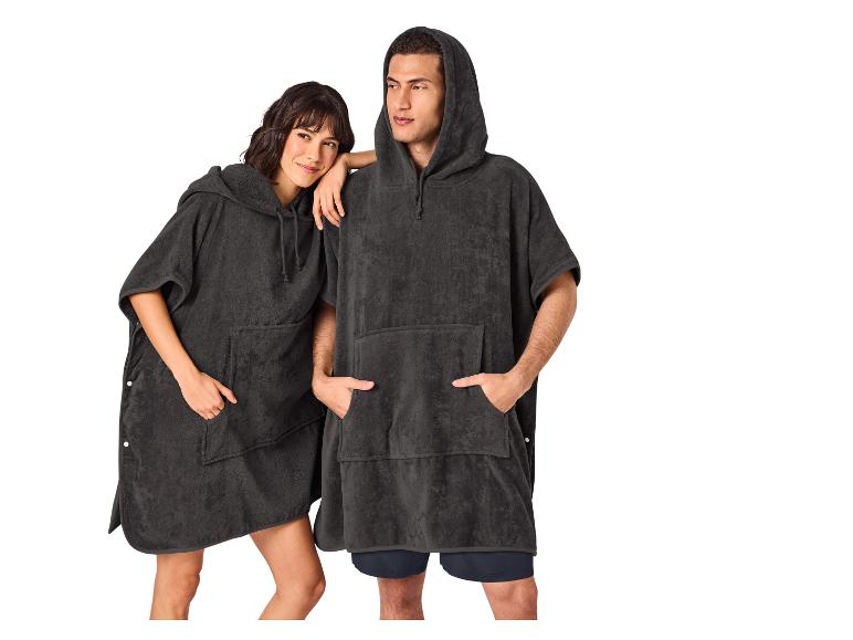 Zwei Personen in dunklen Frottee-Ponchos mit Kapuze und Taschen.