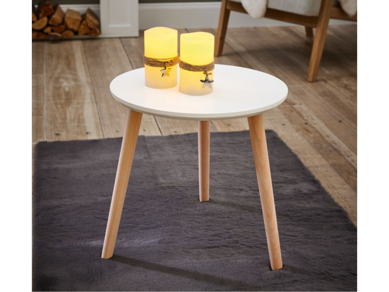 Ein runder Couchtisch mit Holzbeinen und zwei dekorativen Kerzen.