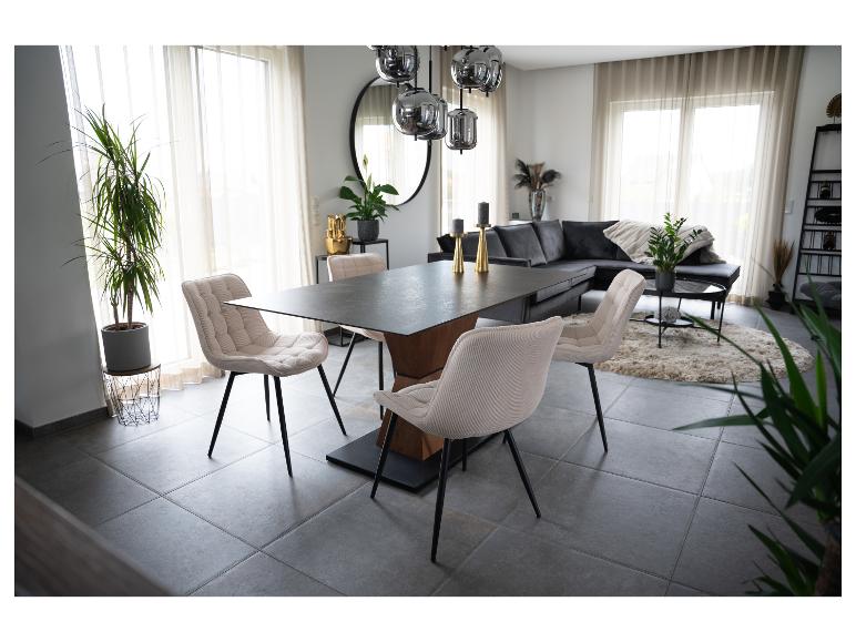 Modernes Esszimmer mit dunklem Holztisch, beigen Polsterstühlen und grauem Sofa.