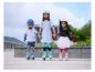 Drei lächelnde Kinder auf Rollschuhen, mit Helmen und Schützern, Hand in Hand.