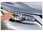 Hand poliert einen matten Autoscheinwerfer, dessen rechte Seite bereits glänzt.