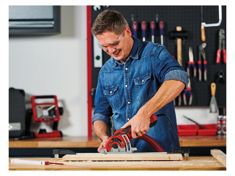 Mann mit Schutzbrille schneidet Holz mit einer Handkreissäge in einer Werkstatt.