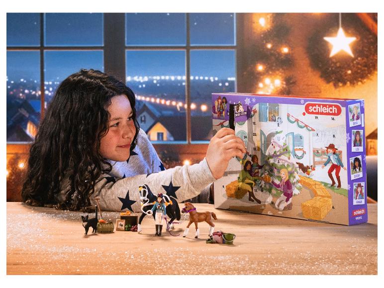 Mädchen öffnet Schleich Horse Club Adventskalender mit Pferdespielzeug und Zubehör.