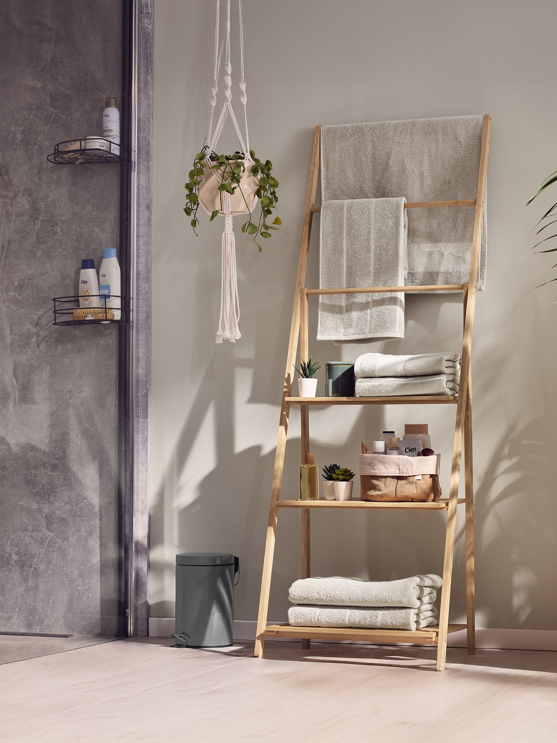 Bambus-Leiterregal mit Handtüchern und Badprodukten in einem modernen Badezimmer.