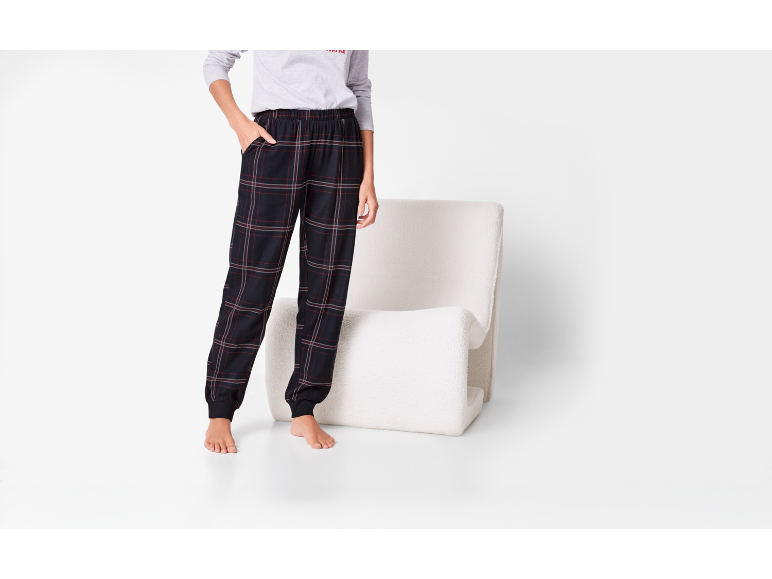 Person in dunkler karierter Pyjamahose mit weißem Stuhl.