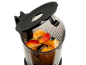 Fruchtstücke in einem Mixer, darunter Orange, Apfel und Mango, mit offenem Deckel.