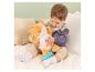 Baby spielt mit weichem orangefarbenen Katzenkuscheltier mit blauem Schwanz und Regenbogenstreifen.