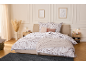 Schlafzimmer mit Bett, floraler Bettwäsche und rosa Kissen.