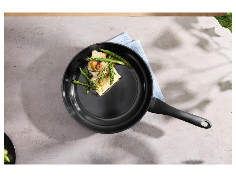 Pfanne mit Fisch und Spargel auf einer grauen Arbeitsplatte mit blauem Tuch