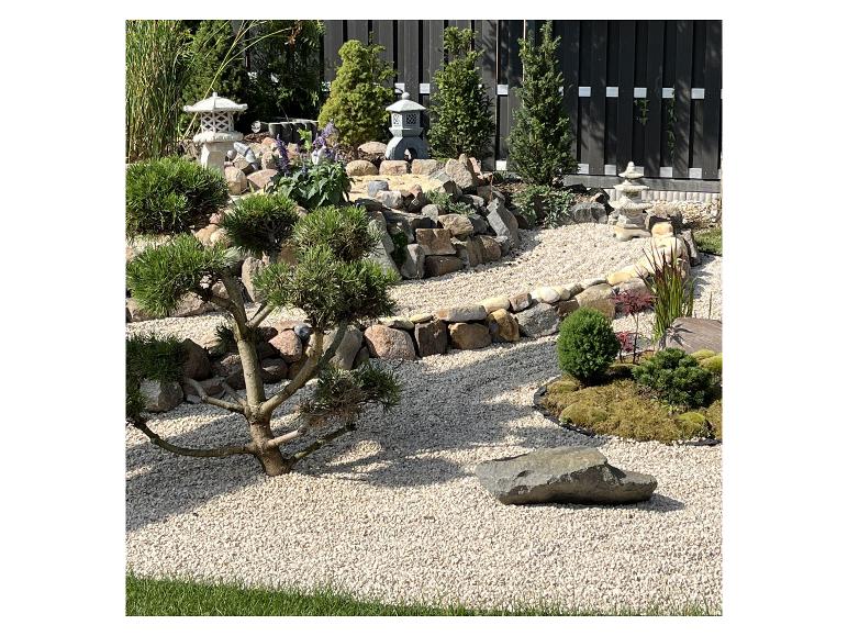 Japanischer Garten mit Bonsai, Steinlaternen und Kiesweg.