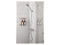 Dusche mit Handbrause, Duschablage mit Flaschen und Schwämmen in einem weiß gefliesten Badezimmer.