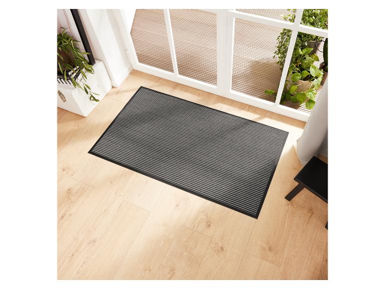 Grau-schwarzer gestreifter Türvorleger auf hellem Holzboden.