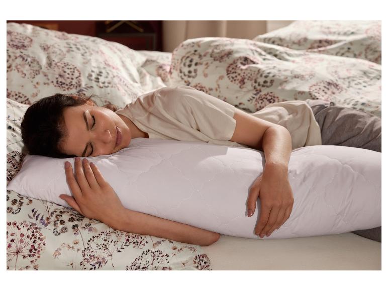 Eine Frau schläft im Bett und umarmt ein weißes LIVARNO home Seitenschläferkissen.