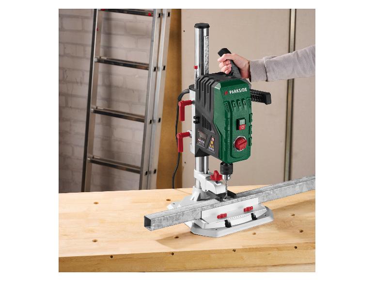 Eine Person benutzt eine Parkside Bohrmaschine, um eine Metallstange auf einer Werkbank zu bohren.