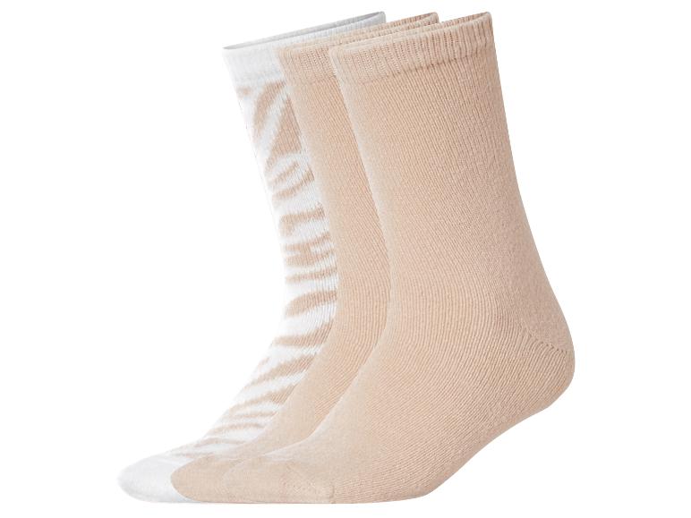 Drei Paar beige und weiße Socken, eines mit Zebramuster.