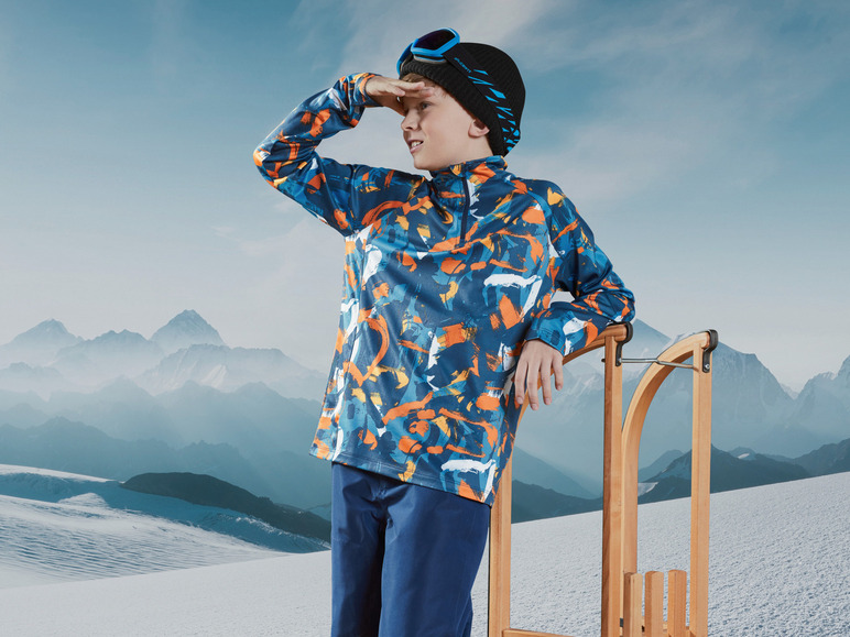 Ein Junge in Skikleidung schaut auf den Schnee