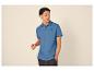 Mann in blauem Poloshirt mit Palmenlogo und dunkler Jeans.