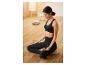 Frau in schwarzem Sport-BH und Leggings in Meditationshaltung.