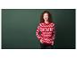Eine Frau in einem roten Pullover mit Schneeflockenmuster vor einem grünen Hintergrund.
