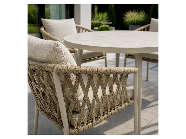 Garten-Essgruppe mit rundem Tisch und geflochtenen Stühlen mit hellen Kissen auf einer Terrasse.