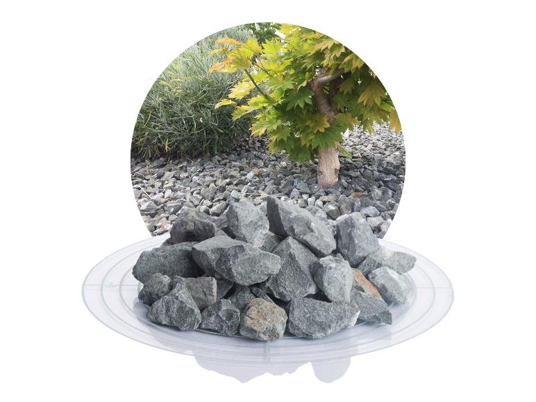Graue Dekosteine auf einem Teller mit Gartenhintergrund.