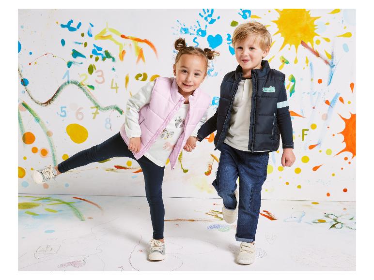 Kinderwesten und Jeans vor einer bemalten Wand.