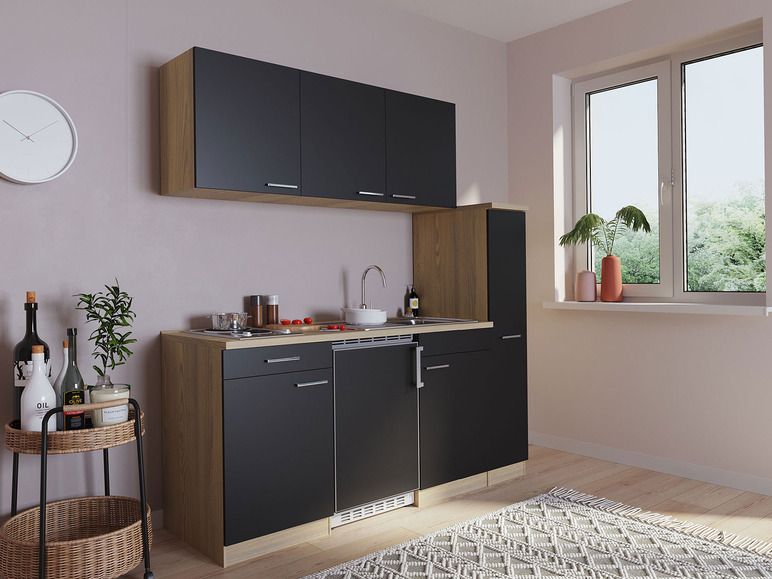 Eine kleine Küche mit schwarzen Schränken, einer Spüle und einem Backofen.