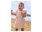 Baby in beigem Blumenkleid am Strand