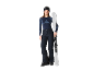 Frau in Skiausrüstung, inklusive Hose, Oberteil und Skibrille, hält Skier.