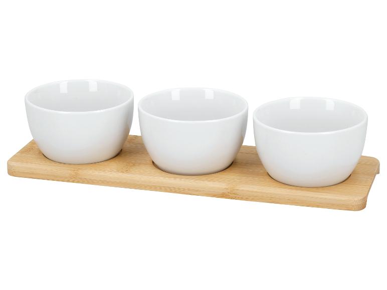 Drei weiße Keramikschalen auf einem Bambustablett.