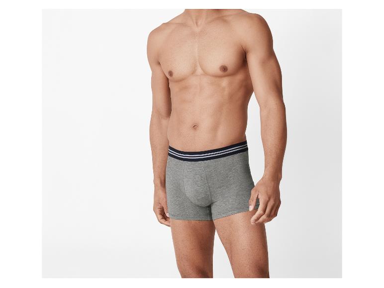 Hemdloser Mann in grauen Boxershorts mit schwarzem Bund und weißen Streifen.