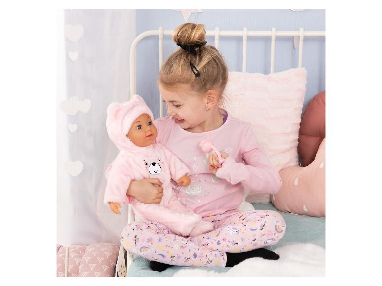 Mädchen im Schlafanzug hält eine Puppe im rosa Bärenkostüm.