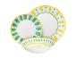 Weißes Geschirrset mit gelben und türkisfarbenen handgemalten Mustern, bestehend aus Tellern und einer Schale.