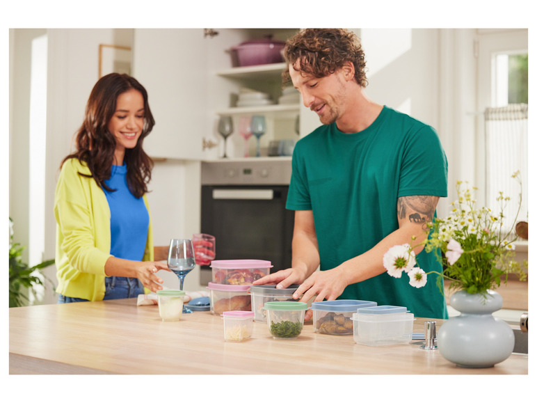 Ein Mann und eine Frau in der Küche mit verschiedenen Aufbewahrungsbehältern, darunter einige von Tupperware.