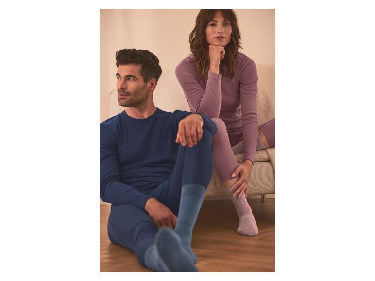 Mann und Frau in bequemen Langarmshirts und Leggings, entspannen sich drinnen.