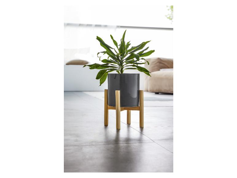 Ein grauer Blumentopf auf einem Holz-Pflanzenständer.
